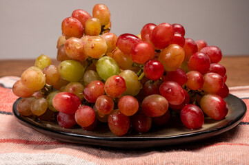 Sweet washed ripe pink grapes berries on board ready to eat