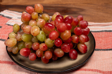 Sweet washed ripe pink grapes berries on board ready to eat