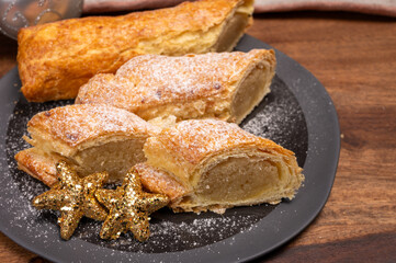 Christmas dessert, fresh baked Dutch filled spicy cookies from puff pastry with almonds on black board close up