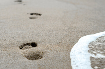 Fototapeta na wymiar footprints in the sand on the beach near the surf