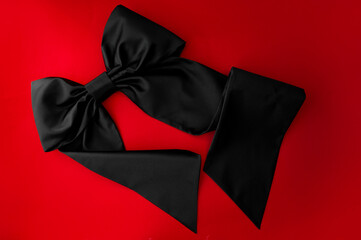 black bow on a red background. silk fabric, black satin. Fashion accessory 2024