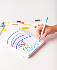School supplies, teenager's hand writing back to school 2024 in Portuguese, white background, selective focus.
