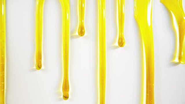 Golden honey or oil flows down on white background.