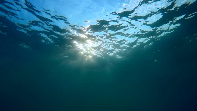 Underwater view on evening sun rays with waves on surface of water, Slow motion. Sunset under surface of water. The light of the sun at sunset time, natural background, Evening Light