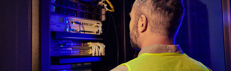 back view of hardworking technician in safety clothes working hard in information center, banner
