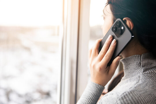 Young Businesswoman Talking On The Phone While Standing In Front Of The Window