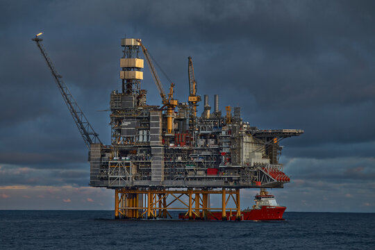 Supply vessel doing cargo operations with jack up drilling rig, offshore platform in the North sea.