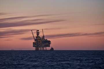 Beautiful colourful seascape with silhouette of a jack up drilling rig and supply vessel doing...