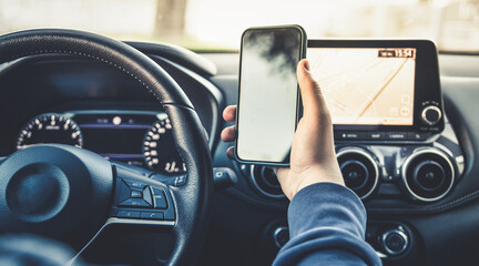 Teen drive a car and use smartphone. Young man reading messages holding a cell phone while driving. Dangerous behavior, accident risk. Danger, transgression, youth, distraction concept. Focus on hand. - obrazy, fototapety, plakaty