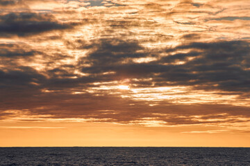 Beautiful colourful sunset sky with yellow clouds in the sea.
