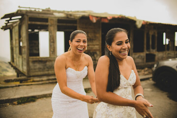 pareja de mujeres usando sus vestidos de boda y sonriendo al aire libre 