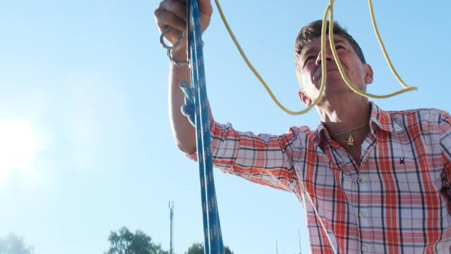 Man ties down sails with ropes finishing working day on yacht. Professional yachtsman brings sailboat in proper look closeup
