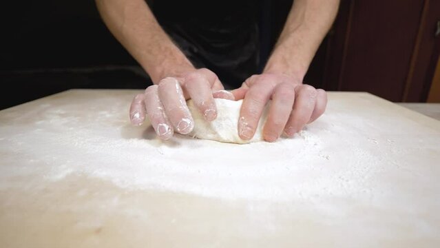Roll out pastry dough. Hands of a young man making dough on a kitchen table