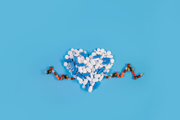 Heart shape from pills with cardiogram. Concept healthcare on blue background.