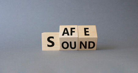 Safe and Sound symbol. Turned wooden cubes with words Safe and Sound. Beautiful grey background. Business and Safe and Sound concept. Copy space