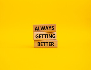 Always getting better symbol. Wooden blocks with words Always getting better. Beautiful yellow background. Business and Always getting better concept. Copy space.