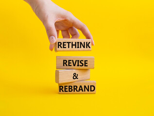 Rethink Revise and Rebrand symbol. Wooden blocks with words Rethink Revise and Rebrand. Businessman hand. Beautiful yellow background. Business and Rethink Revise and Rebrand concept. Copy space.
