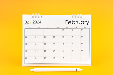 February 2024, Monthly desk calendar for 2024 year and pen on yellow.