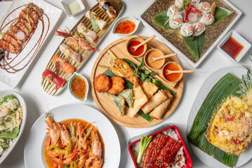 Asian , Chinese, Korean, Japanese and Thai food composition horizontally on white background, from above, with rice dishes, shrimp, sushi, unagi , nigiri, tempura, salad and roll.