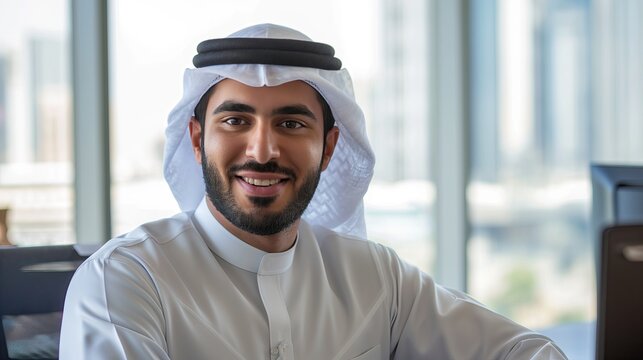 Happy Arab man in office dressed in kandura