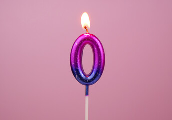 Pink and blue birthday candle burning on pink background. Number 0.