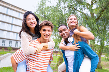 Group of multi-ethnic friends laughing taking a piggyback ride to their girlfriends.