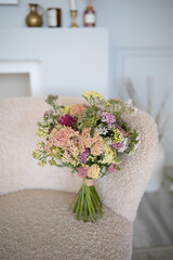 Beautiful bouquet of wild flowers. Stylish chair in the background.