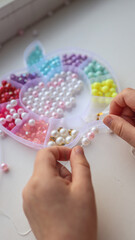 Child makes decoration from beads, creative concept