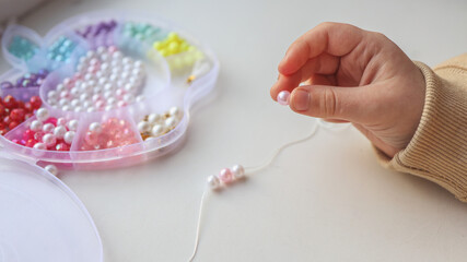 Child makes decoration from beads, creative concept