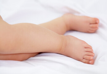 Fototapeta na wymiar Feet, baby and legs of kid on bed for sleep, calm break and relax in nursery room at home. Closeup, foot and toes of tired young child asleep for newborn development, healthy childhood growth or rest