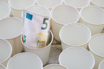 Paper cups with five-euro bill in one of them, donation system, contribution, tips