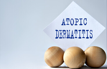 ATOPIC DERMATITIS - words on a white piece of paper on a white background with wooden balls