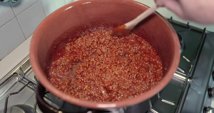 Bolognese sauce cooks in a terracotta saucepan
