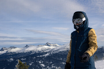 Fototapeta na wymiar Woman in ski or snowboard equipment against backdrop of rocky mountains. Warm jacket, gloves, ski goggles and helmet