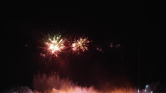 Real fireworks with a large, abstract multi-colored glowing fireworks display with bokeh lights in the night sky. Fiery fireworks display New Year's Eve fireworks celebration 4k