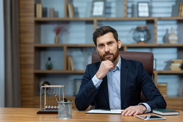 A poised mature businessman reflects deeply while sitting in a classic home office, exuding...