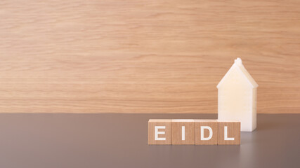 close-up of EIDL wooden cubes on brown background with toy white house