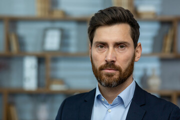 Serious mature businessman with beard in a home office setting, conveying experience, authority,...