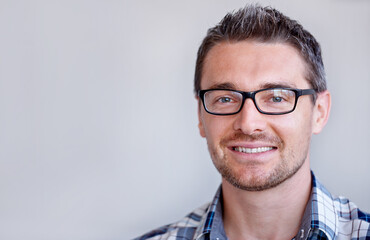 Obraz premium Space, entrepreneur or portrait of happy man with glasses, small business or confidence in studio. Face, designer or employee with smile at startup job, career or company mockup on grey background