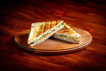 Sandwich with salmon and cucumber. On a wooden table.