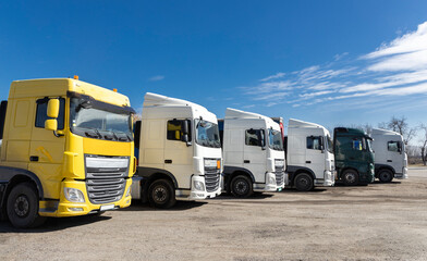 6 trucks parked beautifully in a row on a sunny day. view of the cabs of different colors of...