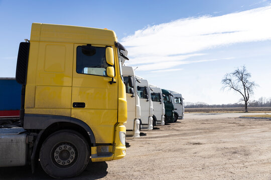 Several trucks parked in a row on a sunny day. view of the cabins of tractor-trailers. Commercial vehicles, cars for business transportation