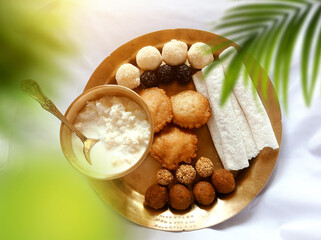 Assamese traditional food items like pitha, laddu, doi sira with assamese gamosa background with japi motifs