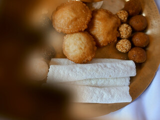 Assamese traditional food items like pitha, laddu, doi sira with assamese gamosa background with japi motifs