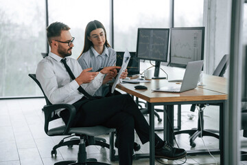 Man is using smartphone. Two employees are working in the office together