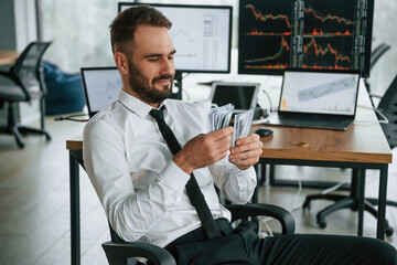 Counts money. Businessman is sitting by computer and working in the office