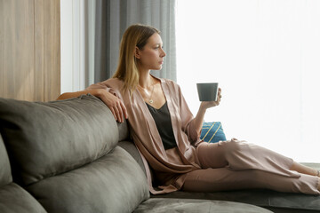 Woman in satin loungewear resting and sitting in the living room	