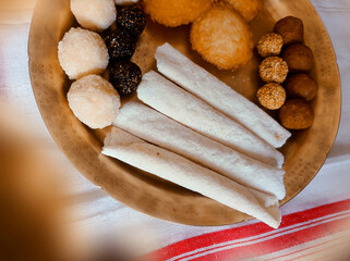 Assamese traditional food items like pitha, laddu, doi sira with assamese gamosa background with...