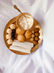 Assamese traditional food items like pitha, laddu, doi sira with assamese gamosa background with japi motifs