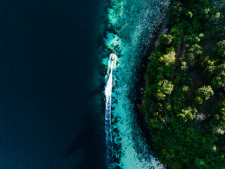 View from above, stunning aerial view of a longtail boat sailing on a turquoise water. Phuket, Thailand.